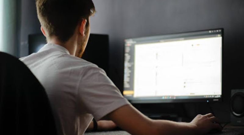 A man sitting at a computer, focused on a monitor, illustrating AI tools for enhancing customer engagement.
